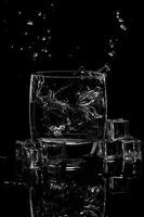 water splashing in a glass of water and ice on blackbackground photo