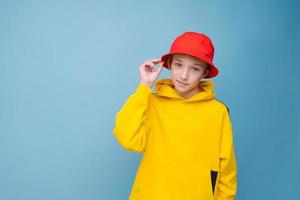 Portrait of a positive guy in a yellow sweater and red panama hat on a blue photo