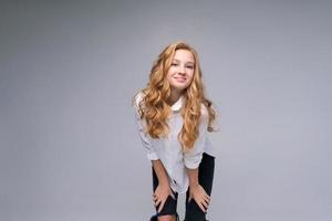 A young girl teenager posing in studio on gray background in white shirt photo