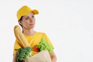 Smiley delivery woman in yellow posing with grocery bag, white background photo