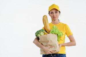 Smiley delivery woman in yellow posing with grocery bag, white background photo