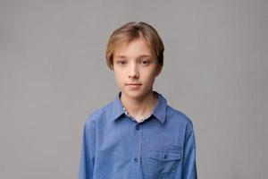 Happy millennial caucasian guy in blue shirt isolated on gray studio background photo