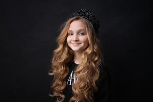 Beautiful little princess girl in black clothes with a crown on her head posing photo