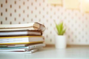 Desktop stack of notebooks and  flower in the background, soft focus photo