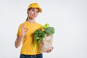 A woman in yellow clothes, delivering a package of food, on a white background photo