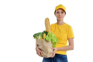 mujer de entrega sonriente en amarillo posando con bolsa de supermercado, fondo blanco foto