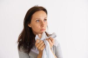 Woman sniffing clean shirt on light background photo