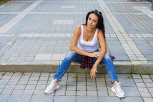 Happy young fashion woman sitting on the street sidewalk stylish female model photo