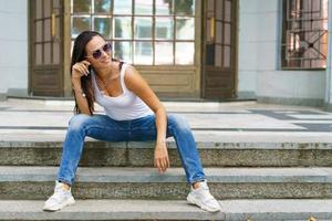 Beautiful caucasian woman with glasses sits on the street in a crowded city photo