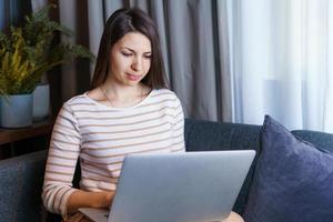 Cheerful young woman relaxing at home after work, talking with friend or photo