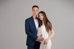 Happy caucasian hugs his girlfriend on gray background. Professional successful photo