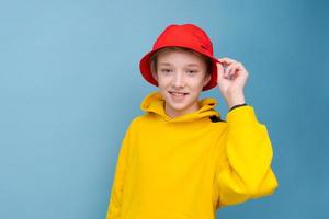 Portrait of a positive guy in a yellow sweater and red panama hat on a blue photo