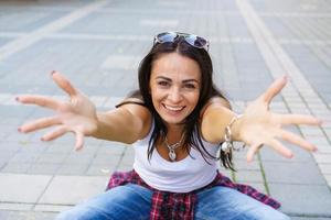 feliz moda joven mujer sentada en la acera de la calle elegante modelo femenino foto