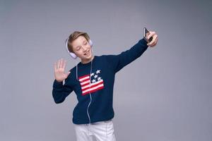 Portrait young cheerful guy in blue sweater with flag of usa with headphones photo