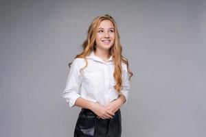 Young blonde woman dressed in white shirt in relief, stands relaxed and smiles photo