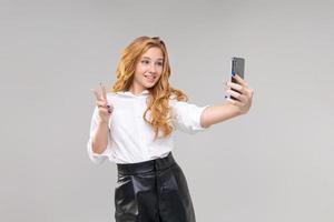 Young caucasian girl communicates by video communication using phone photo