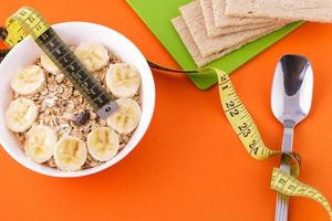 oatmeal  and crispbread lie with spoon and measuring tape on orange background photo