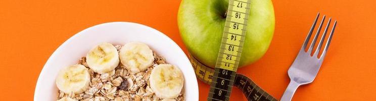 muesli con plátano sobre fondo naranja con manzana y cinta métrica foto