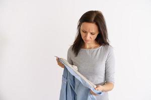 Woman look at dirty shirt on light background photo