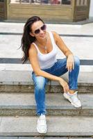 Beautiful caucasian woman with glasses sits on the street in a crowded city photo