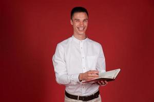 Happy businessman smiling and writing in notepad with pen while wearing white photo