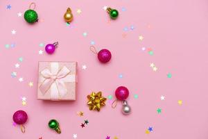 caja de regalo envuelta con cinta, bolas decorativas y copos de nieve en rosa colorido