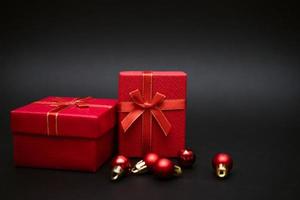 Red gift box with balls for decorating a Christmas tree on a black background photo