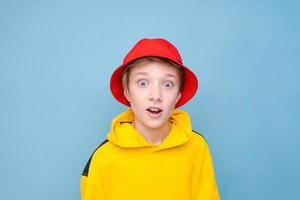 Portrait surprised young guy in yellow sweater and red panama hat on a blue photo