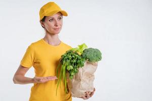 A woman in yellow clothes, delivering a package of food, on a white background photo