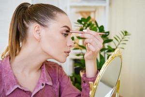 joven bloguera atractiva hablando de belleza. muestra cómo aplicar el maquillaje foto