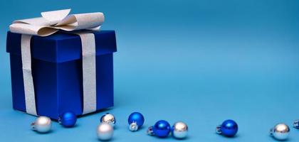 caja de regalo azul con bolas de navidad sobre fondo azul foto