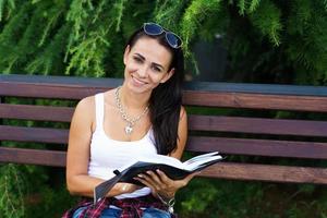 Freelance caucasian girl sits on bench and writes in a notebook. Education photo