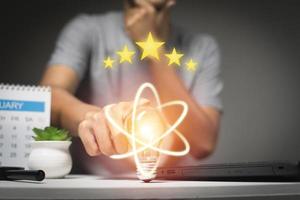 Hand holding lightbulb Five golden rating star and idea saving energy and business technology concep photo
