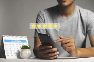 Man hand using smartphone with popup five star icon for feedback review satisfaction service photo