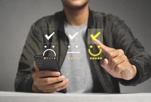Customer satisfaction survey concept, Man using Smartphone select smiley face icon with yellow five stars photo