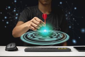 Man throwing red arrow dart to virtual target dart board. technology concept photo