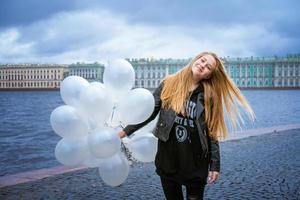 chica alegre feliz divirtiéndose con grandes globos de látex blanco. al aire libre en el foto