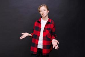 Cute little boy in white t-shirt and red shirt in cage posing on black photo
