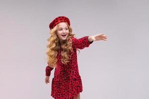 Little girl in french style hat points her finger to side. Happy girl with long photo