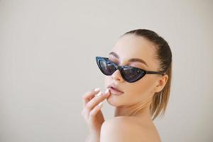 Fashionable young lady, stylish girl with beautiful face in fashionable glasses photo