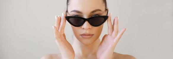 Fashionable young lady, stylish girl with beautiful face in fashionable glasses photo