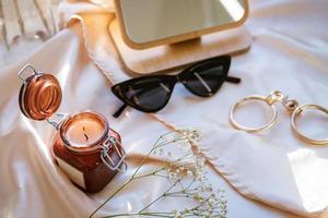 there is a decorative candle in a jar and glasses on the fabric photo