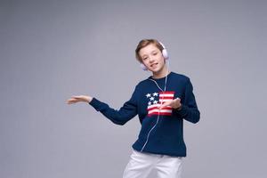 Joyful young man in blue sweater with flag america, stands listening to music photo