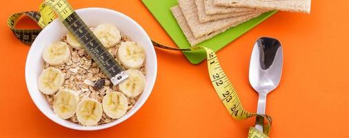 oatmeal  and crispbread lie with spoon and measuring tape on orange background photo