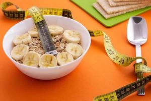 oatmeal  and crispbread lie with spoon and measuring tape on orange background photo