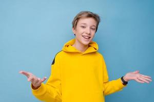 Young smiling happy cheerful man in bright yellow sweatshirt pointing photo