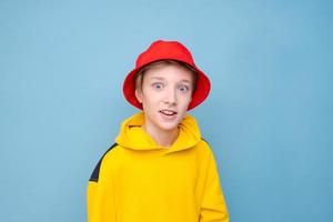 retrato de un tipo positivo con un suéter amarillo y un sombrero de panamá rojo en un azul foto