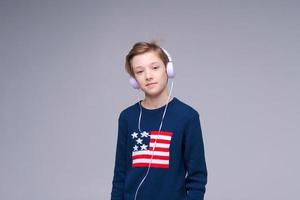 Happy caucasian boy wearing wired headphones listening to music with contented photo