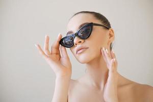Sexy glamorous female model in fashionable sunglasses with hand on her face