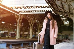 Woman traveler tourist walks with luggage at the train station. The concept of photo